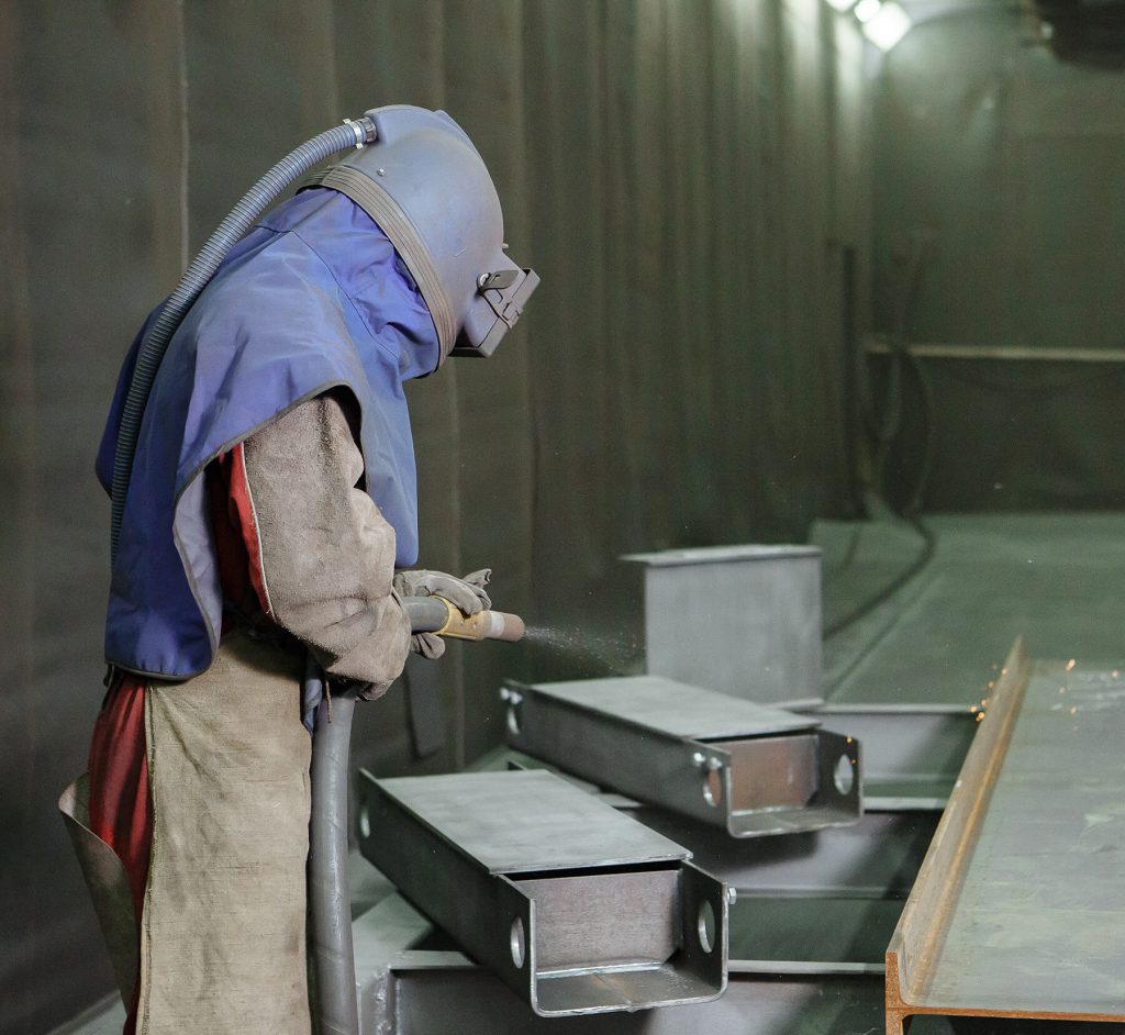 sandblast employee prepares metal part 1024x942